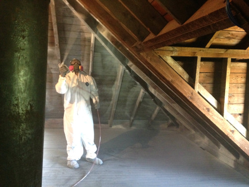 Attic Restoration Sealant Person in suit cleaning attic